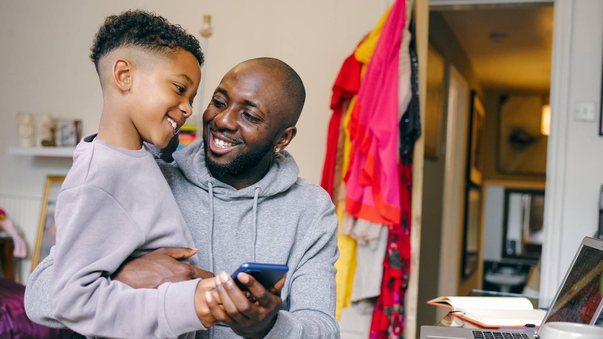 an adult and son smiling and holding a blue phone