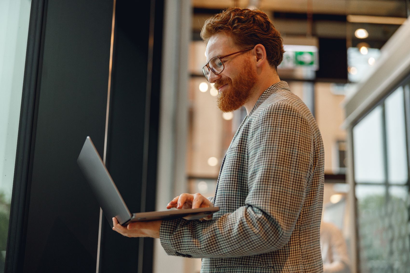 Image 11 red haired bearded man with glasses smiling at his laptop