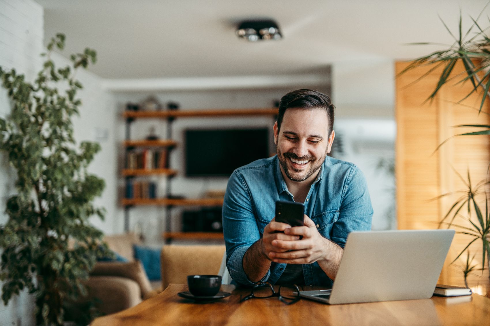 Image 4 a man sitting at a desk and laughing at something on his phone